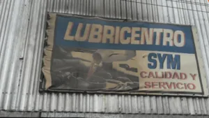 El cartel de identificación de un lubricentro ubicado en la intersección de calle Rouillón y La Paz, en el barrio Urquiza de Rosario, cubierto por manchas negras de hollín. Los rastros del fuego son visibles sobre la estructura metálica y el nombre del comercio como consecuencia del ataque incendiario registrado durante la última noche.