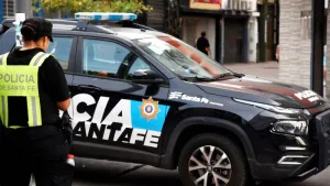 Fotografía de archivo de un patrullero de la Policía de la Provincia de Santa Fe estacionado en la calle, con las luces de emergencia apagadas. El plano es medio y enfoca el lateral del vehículo donde se lee la inscripción de la fuerza de seguridad sobre un fondo oscuro con tonos azules y negros.